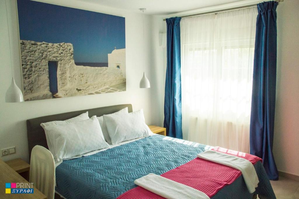 尼亚普拉莫斯Evaggelia Design Suite的一间卧室配有床和蓝色窗帘的窗户