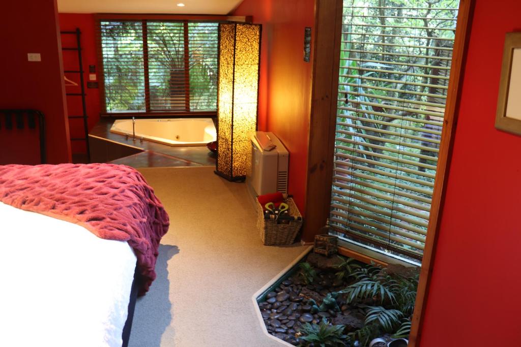 丹德农山林登花园雨林住宿加早餐旅馆的一间带浴缸、床和窗户的卧室