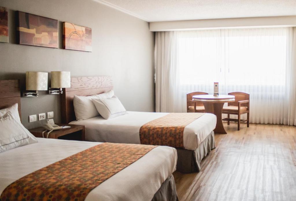 克雷塔罗Hotel Mirage - Centro Histórico de Querétaro的酒店客房设有两张床和一张桌子。