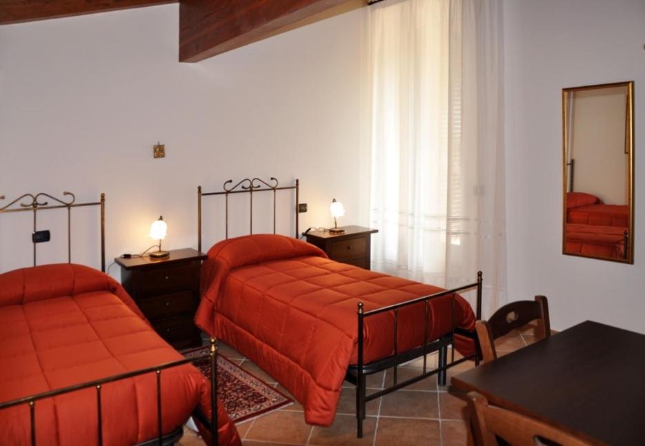 特拉莫安蒂卡因特拉姆尼亚住宿加早餐旅馆的一间卧室配有两张带红色床单和桌子的床