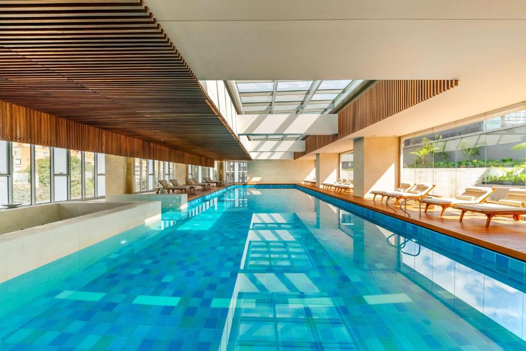 波哥大Grand Hyatt Bogota的大楼内一个带桌椅的游泳池