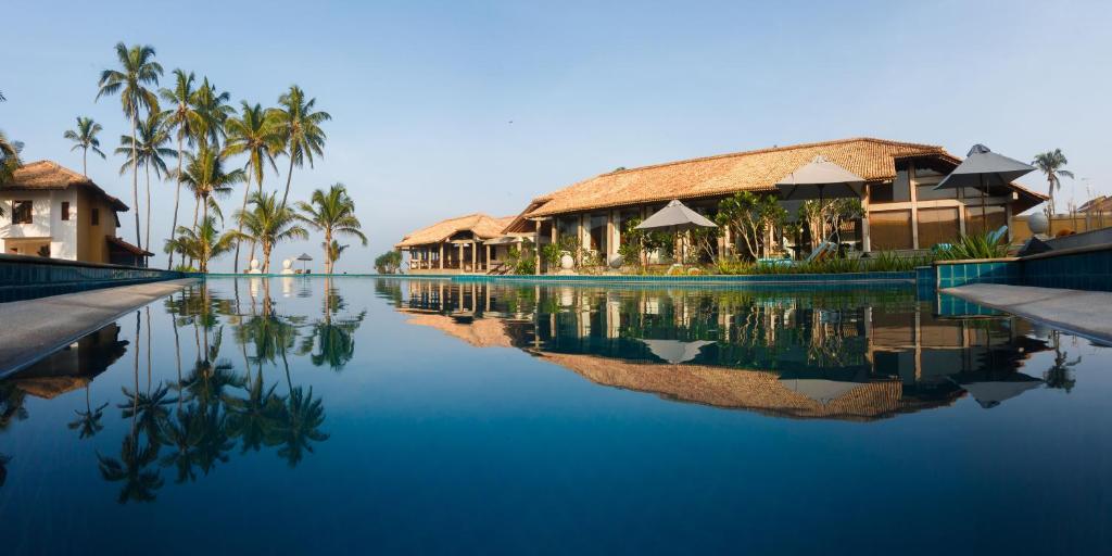 尼甘布Wattura Resort & Spa的棕榈树和建筑的度假游泳池