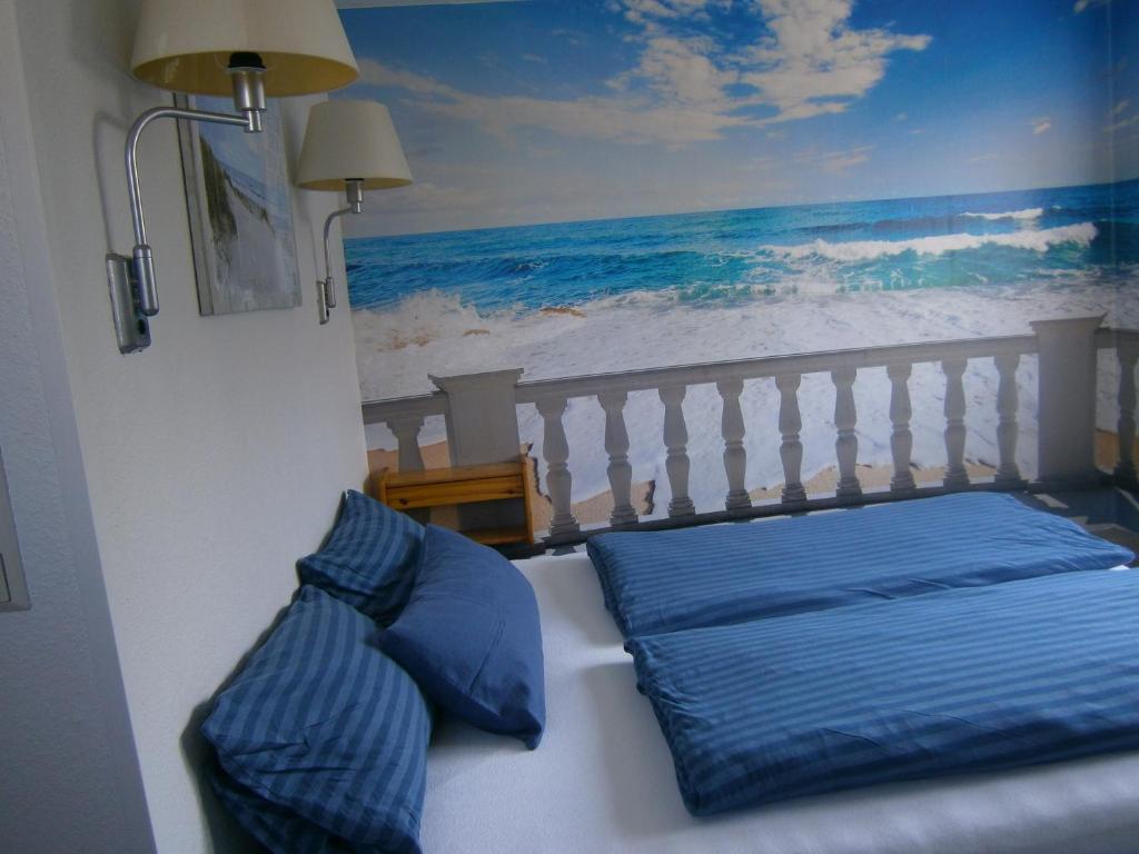 克伦胡森Haus Steinbach的一张带蓝色枕头的床和一幅海洋画