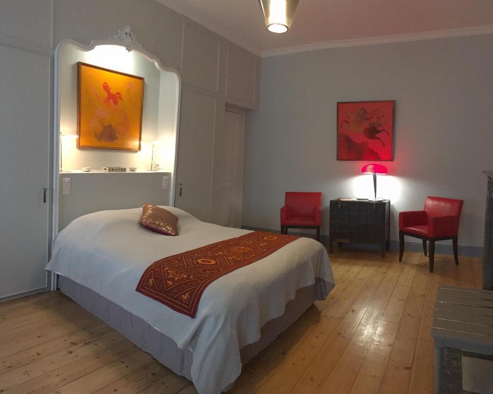 杜埃LES CHAMBRES D'HOTES DU PALAIS的一间卧室配有一张床和两张红色椅子