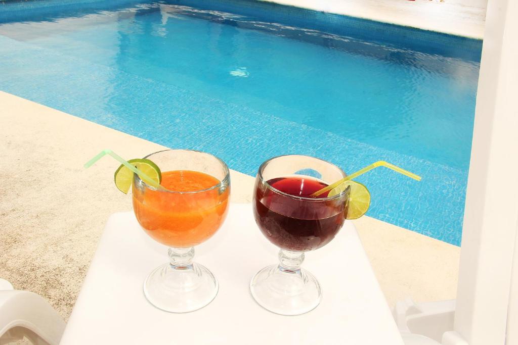 坎昆Amazing Mexican Airport Inn的游泳池旁托盘上的2杯鸡尾酒