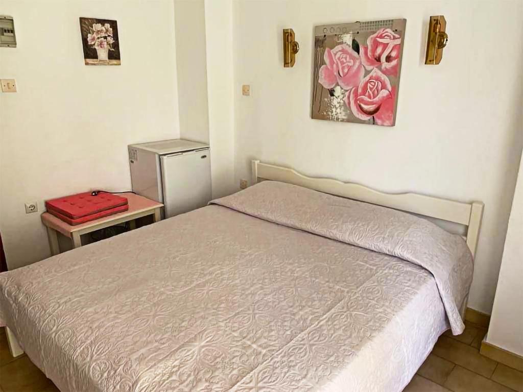 毕达哥利翁Sunshine Pension的一间卧室配有一张床和一张桌子,并装有红色的行李箱