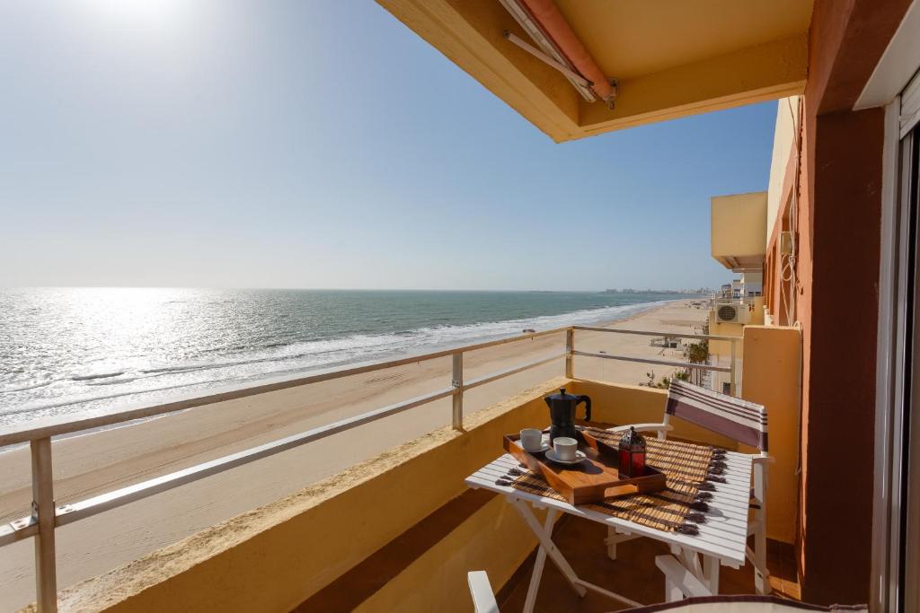加的斯ALTAMAR Sunny Home by Cadiz4Rentals的阳台配有桌子,享有海滩美景