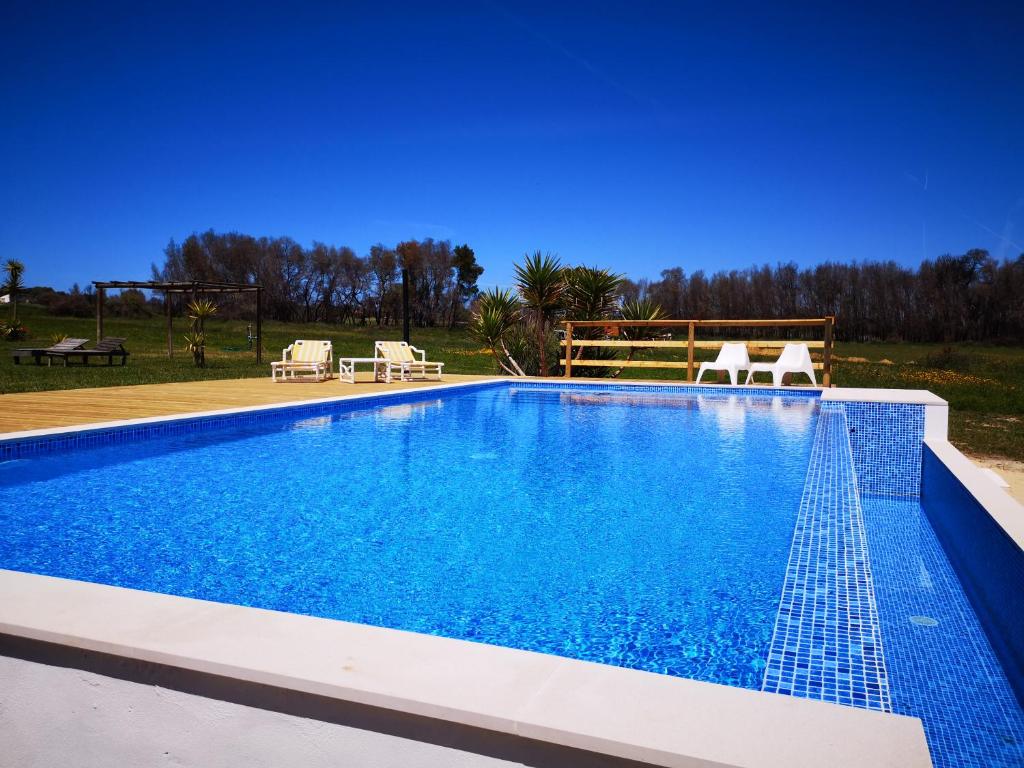 阿尔热祖尔Quinta de Moledos的一个带蓝色水和两把椅子的游泳池