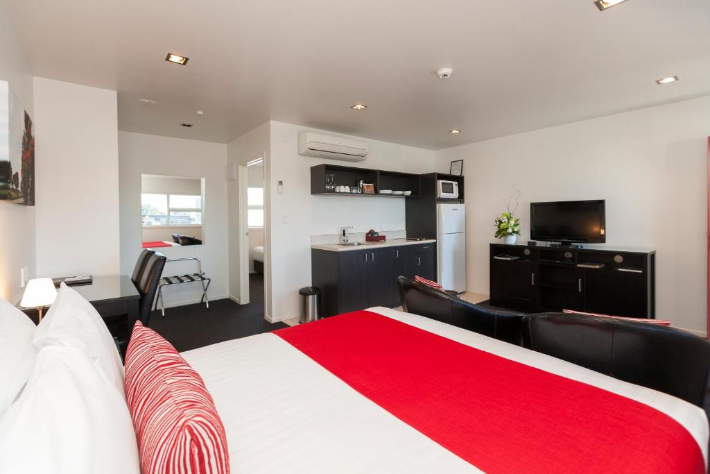 新普利茅斯道森汽车旅馆的一间带红色和白色床的卧室和一间厨房
