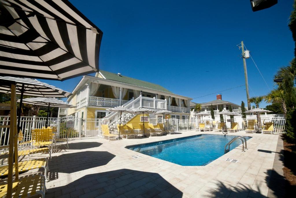 泰比岛Georgianne Inn & Suites check in 212 Butler Ave的房屋前的带椅子和遮阳伞的游泳池