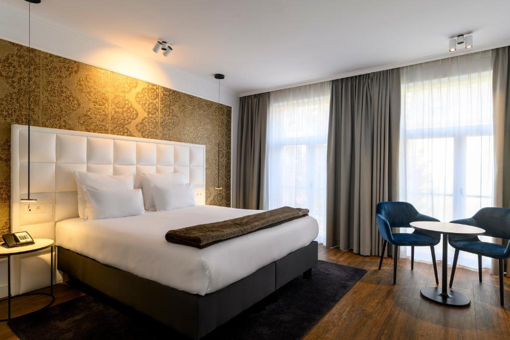 安特卫普鲁本斯大广场酒店的酒店客房带一张床、一张桌子和椅子