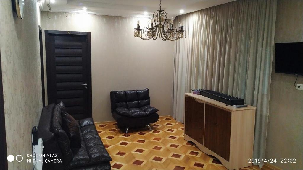 第比利斯Guest House Asthik的客厅配有黑色皮椅和电视
