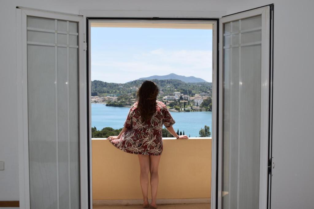 科孚镇Elite Corfu Sea View Rooms的站在窗外的阳台上的女人