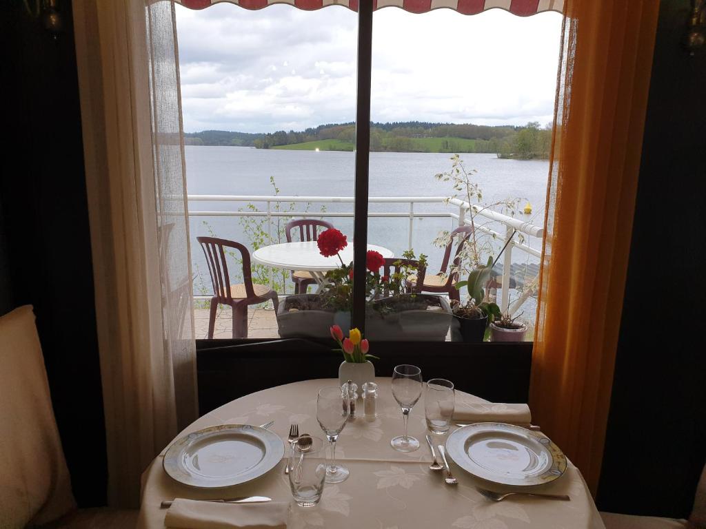Peyrat-le-ChâteauHotel Restaurant La Caravelle的一张桌子,从窗口可欣赏到水景