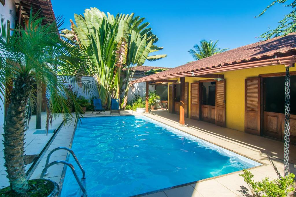 帕拉蒂Pousada Acquarela的棕榈树屋前的游泳池