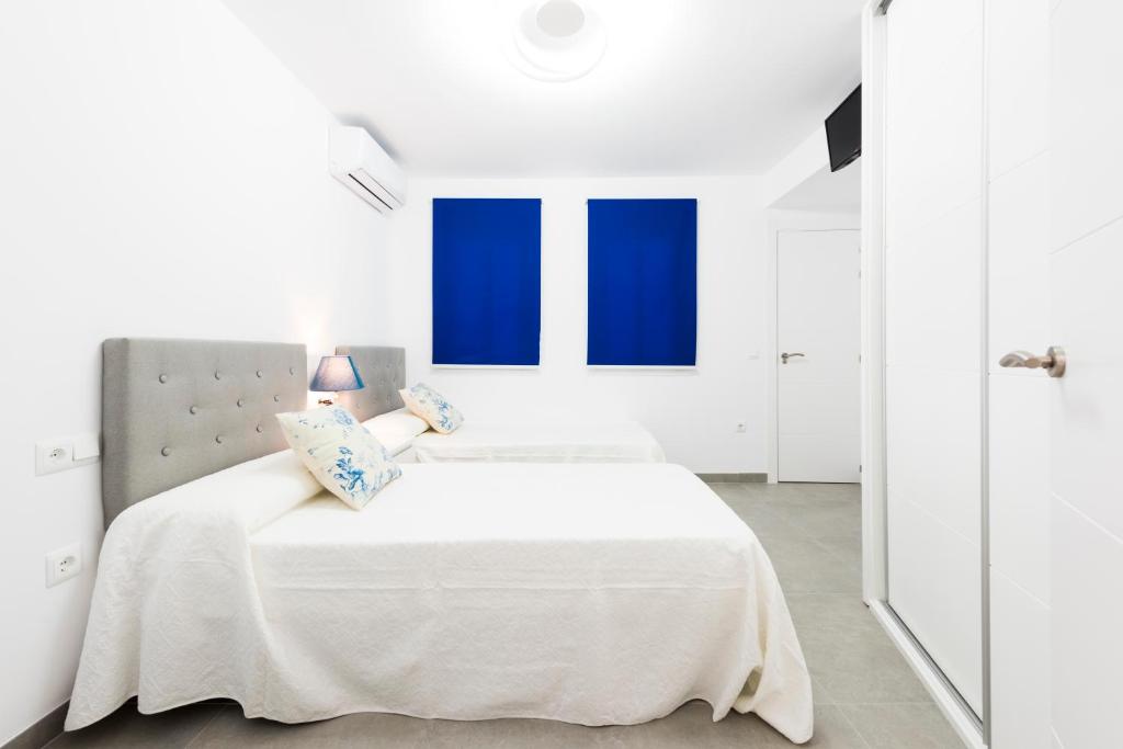 内尔哈EDIFICIO SUR的白色卧室设有蓝色窗户和床。