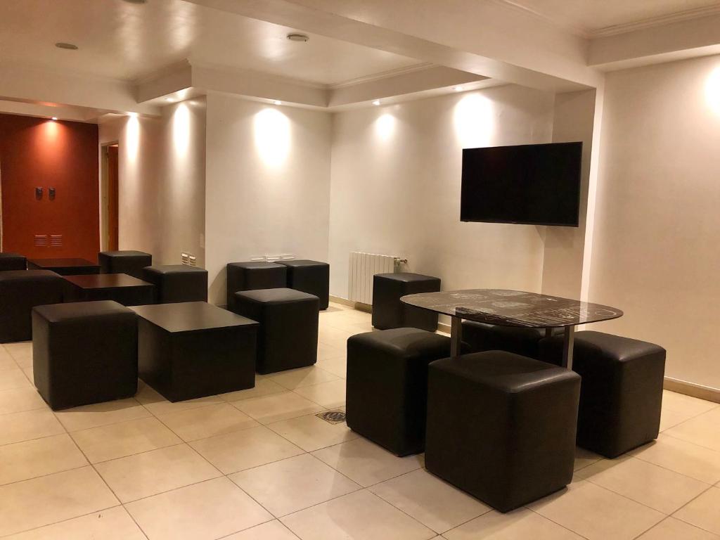 科尔多瓦Hotel Petit的一间设有桌子、凳子和平面电视的等候室