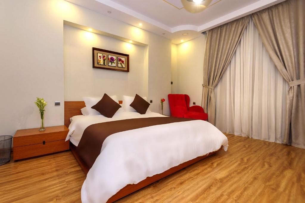 开罗Arabella Residence的酒店客房设有一张大床和一张红色椅子。