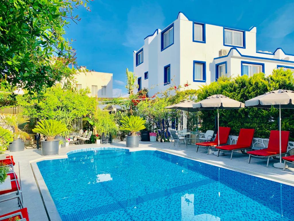 博德鲁姆阿屯博德鲁姆酒店的一座带椅子和遮阳伞的游泳池位于一座建筑旁边
