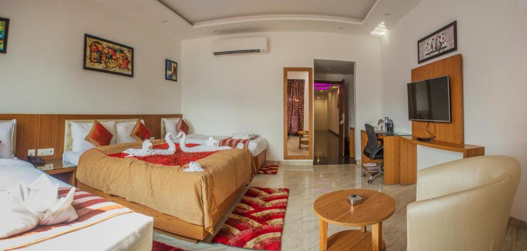 西里古里Hotel Suktara International的酒店客房设有两张床和电视。