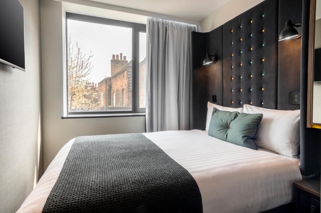 伦敦A点伦敦利物浦街酒店的一间卧室设有一张大床和窗户