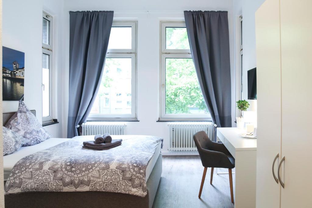杜塞尔多夫dreams Düsseldorf的一间卧室配有一张床、一张书桌和两个窗户。