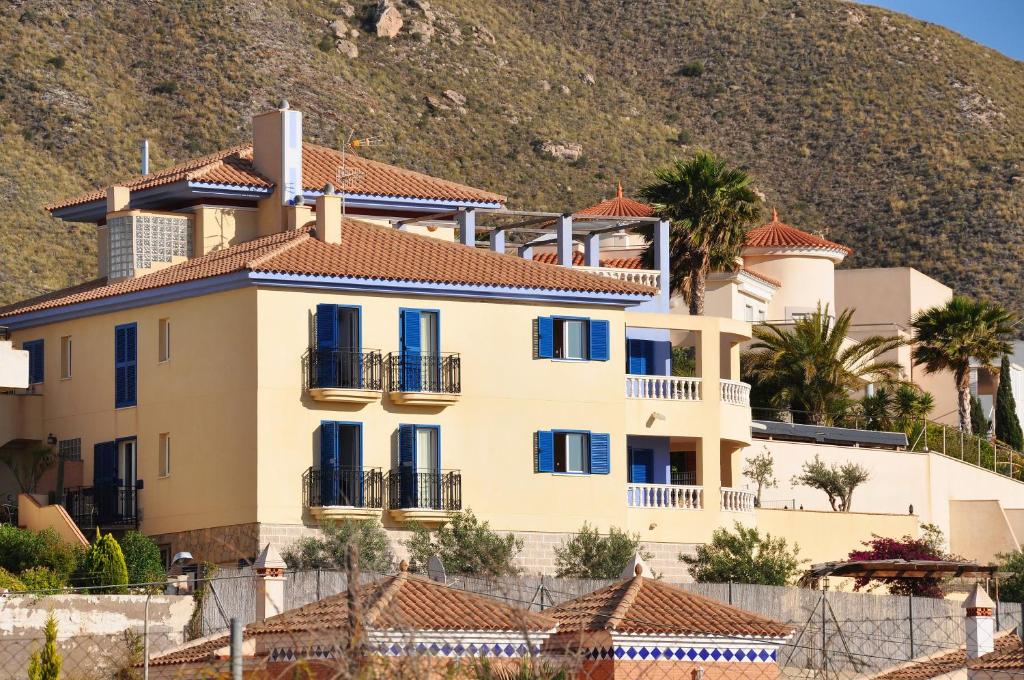 卡拉芭蒂纳玛雅里酒店的一座带蓝色窗户和山丘的大型黄色房屋