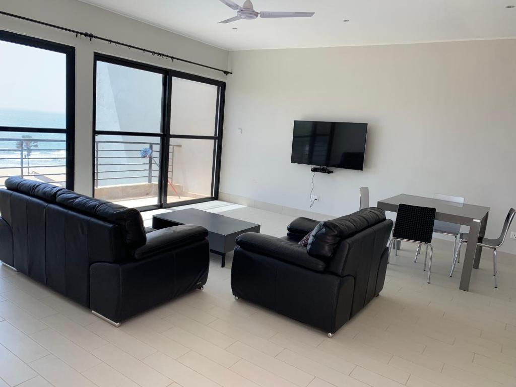 Sere Kunda NDingWATERFRONT FLAT的客厅配有两张沙发、一张桌子和一台电视机
