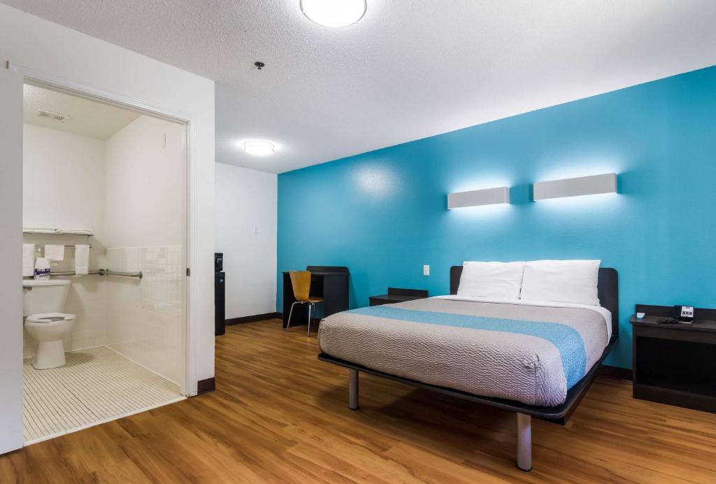 格尔夫海岸海湾海岸6号汽车旅馆的一间卧室设有一张床和蓝色的墙壁