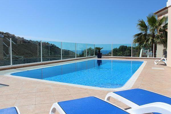 莫莱拉Villa Guapa With Gym Aircon Wifi Moraira的一个带椅子的游泳池,背景是大海