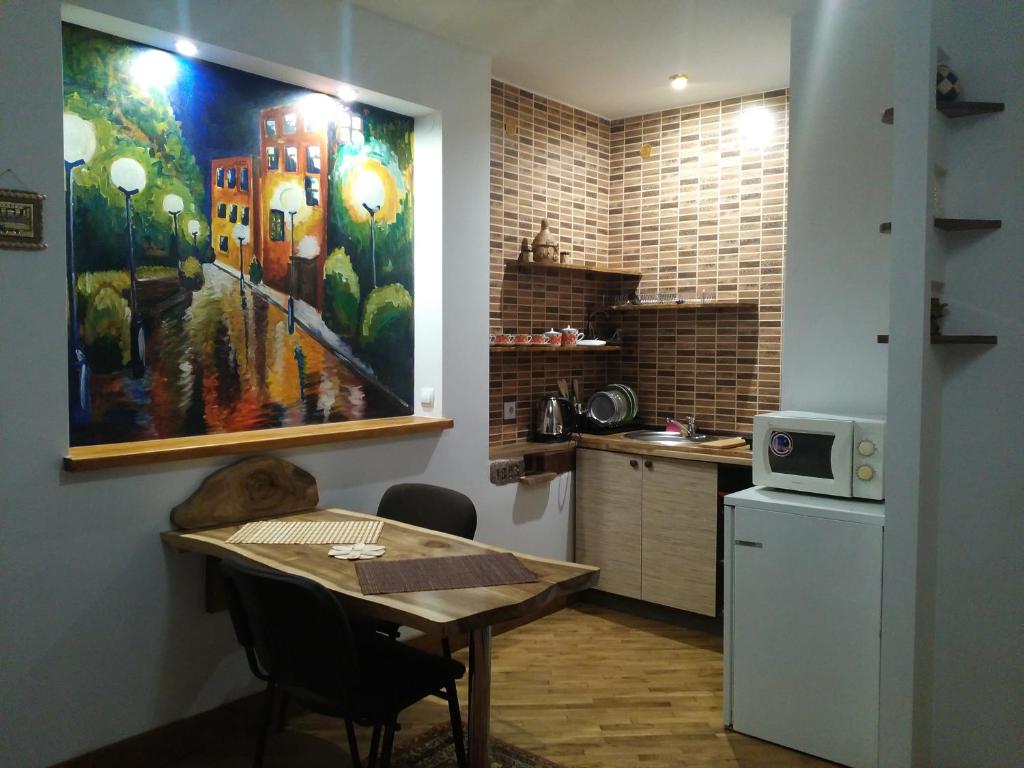 特鲁斯卡韦茨Квартира-студія Шале的厨房配有桌子,墙上挂有绘画作品