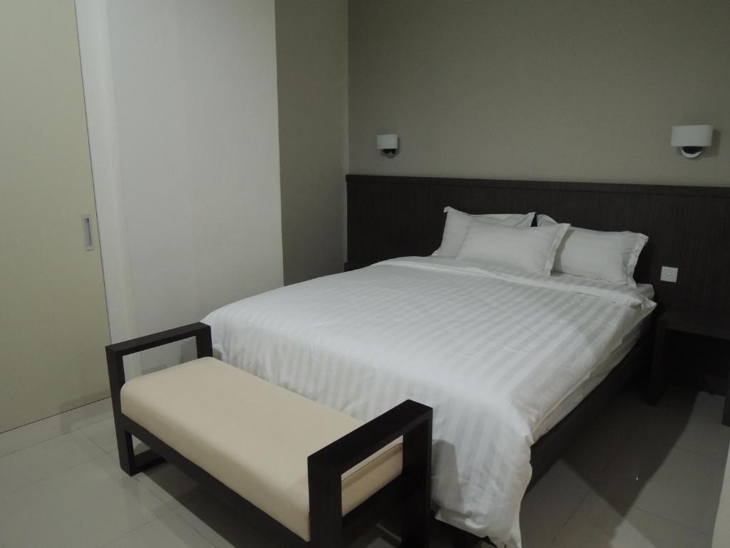雅加达哈利斯公寓的卧室配有一张白色大床和一把椅子