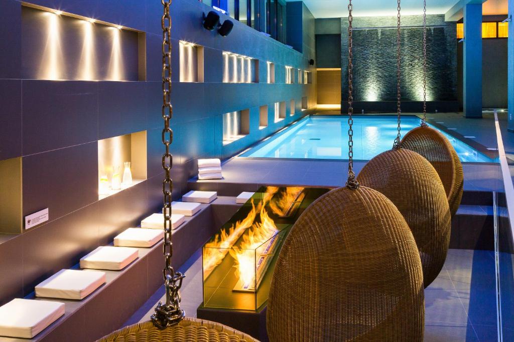 夏蒙尼-勃朗峰Heliopic Hotel & Spa的一个带椅子和秋千的游泳池