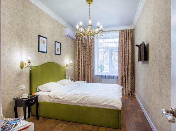尼古拉耶夫Люкс-апартаменты с двумя спальнями的一间卧室配有一张绿色的床和吊灯。