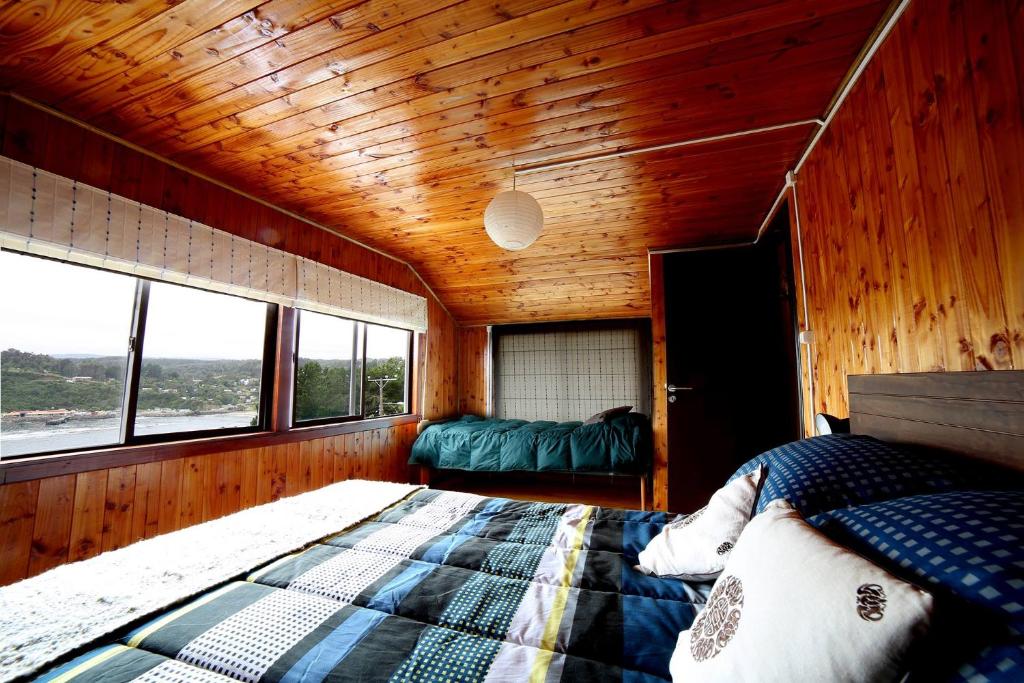 巴拉曼萨Hostería La Casa del Mar的木制客房 - 带窗户和1张床铺的卧室