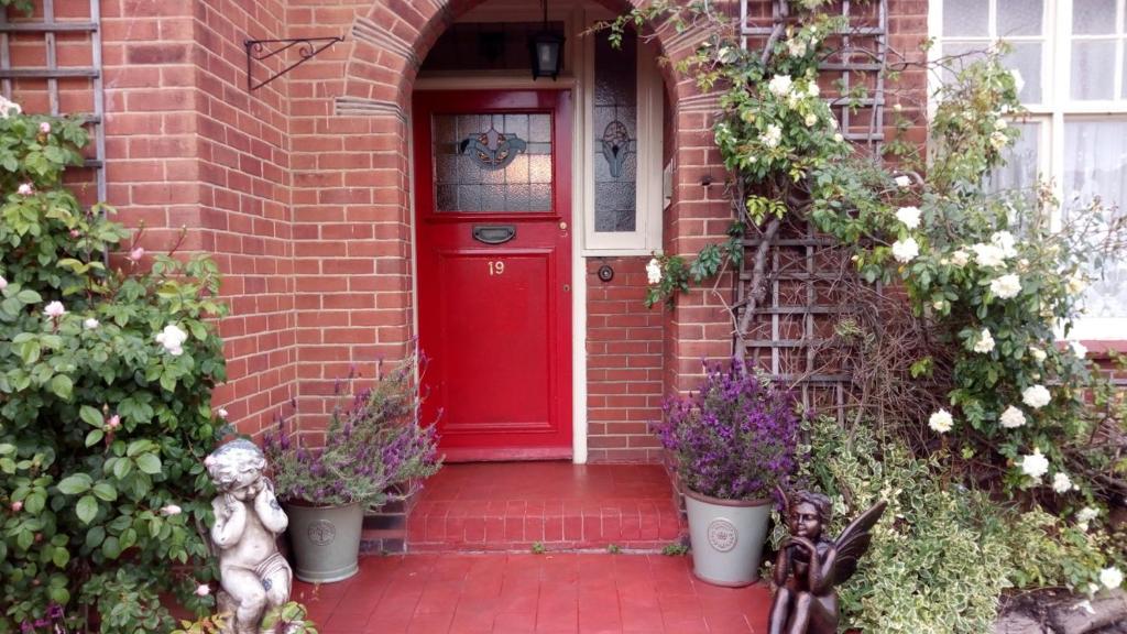 布罗克斯本Kingsway Bed & Breakfast的砖房里一扇红门,花朵花