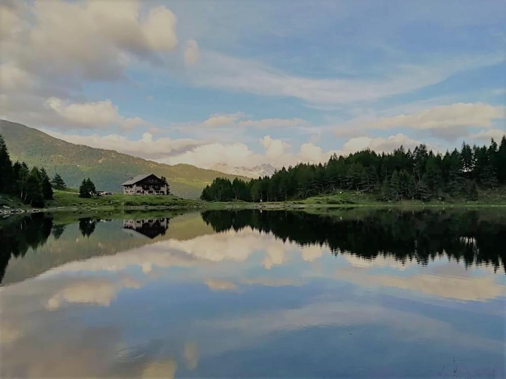 MonnoRIFUGIO AL LAGO DEL MORTIROLO in inverno raggiungibile solo a piedi的湖水上房屋的倒影