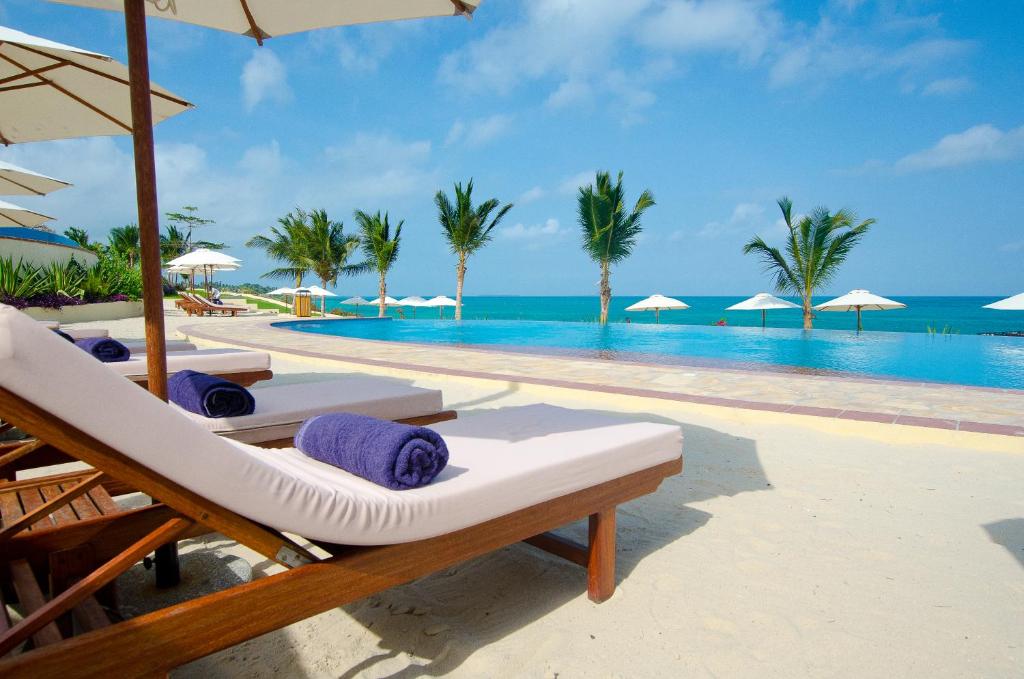 桑给巴尔海崖水疗度假酒店的一个带椅子和遮阳伞的度假游泳池以及大海