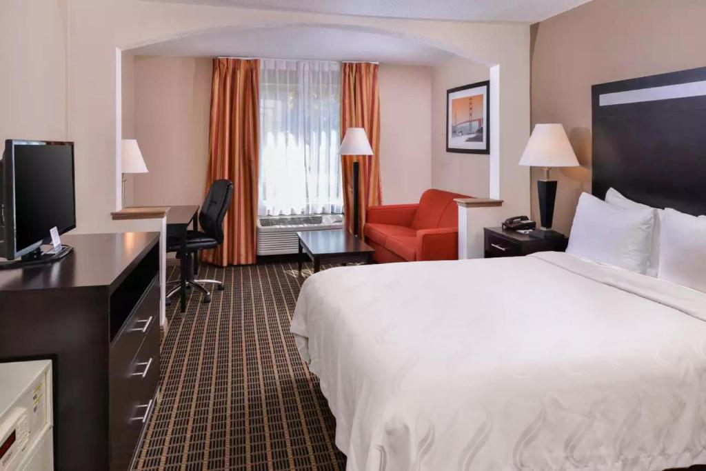 南旧金山Hotel Nova SFO By FairBridge的酒店客房设有一张大床和一张红色椅子。