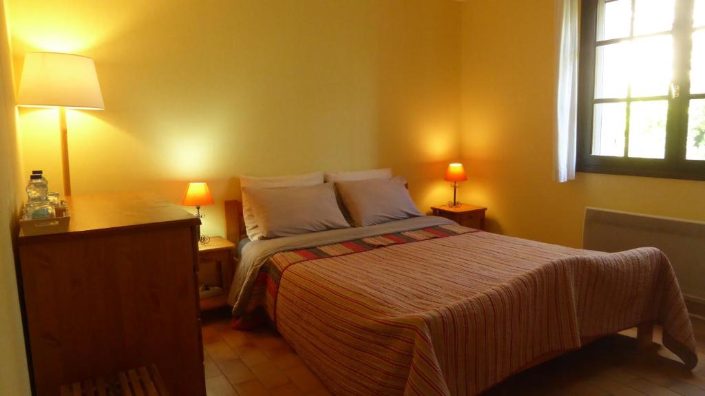 锡富尔勒普拉日Les Pucines T2 bas de villa的一间卧室配有一张床、两盏灯和一个窗户。