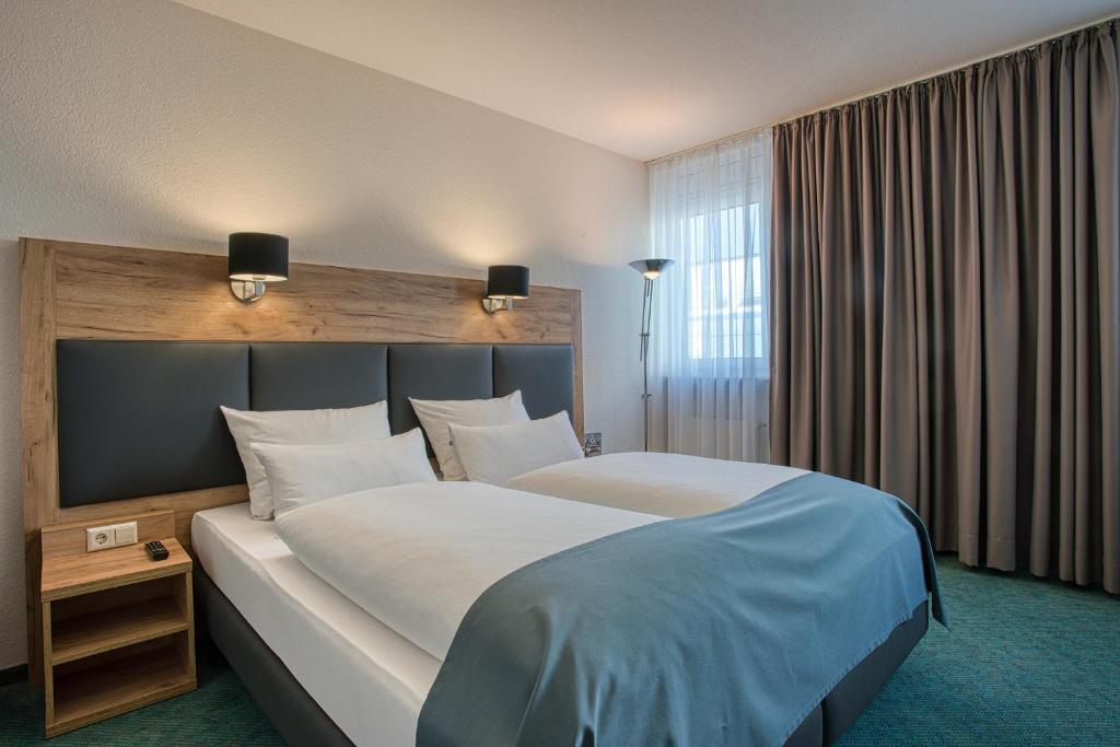 伯布林根Centro Hotel Böblingen的一间设有大床和窗户的酒店客房