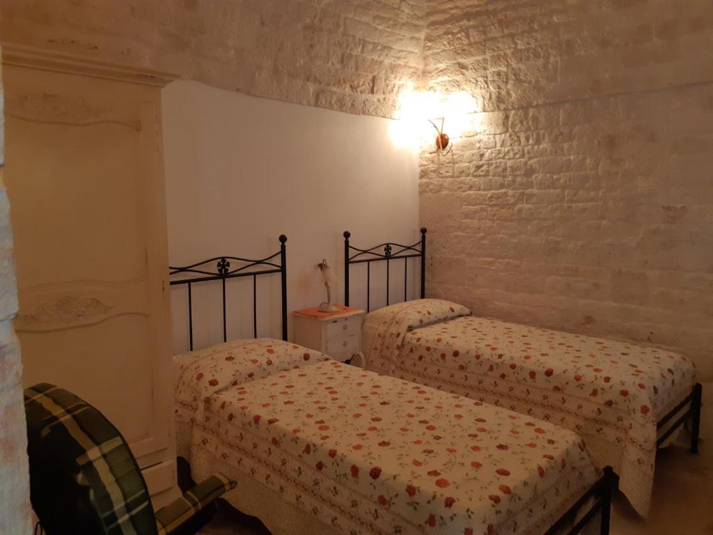 阿尔贝罗贝洛Alberobello Casa Vacanze - Pathos tra i Trulli的一间卧室设有两张床和砖墙