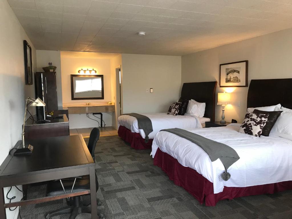 罗克斯普林Country West Motel of Rock Springs的酒店客房设有两张床、一张桌子和一台电视。