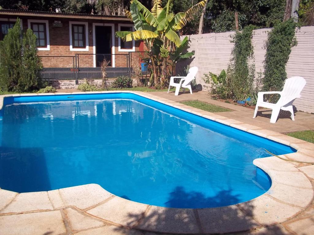 伊瓜苏港皇家伊瓜苏旅馆的蓝色游泳池,带两把椅子和房子