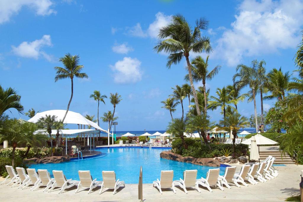 塔穆宁关岛凯悦酒店的一个带躺椅和棕榈树的度假游泳池