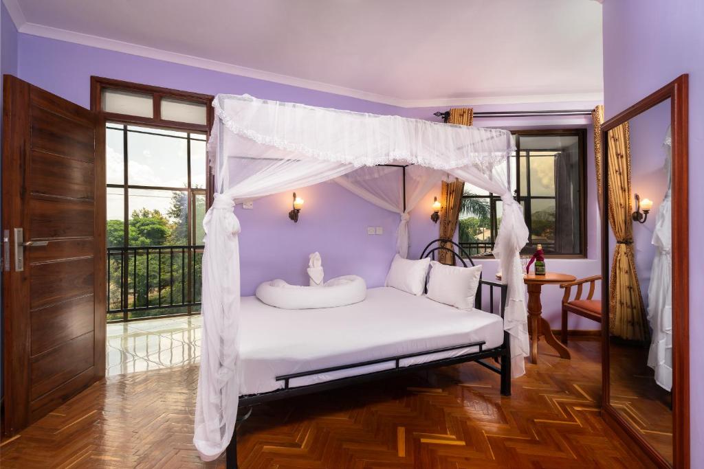 阿鲁沙Mrimba Palm Hotel的一间卧室配有一张带天蓬的床