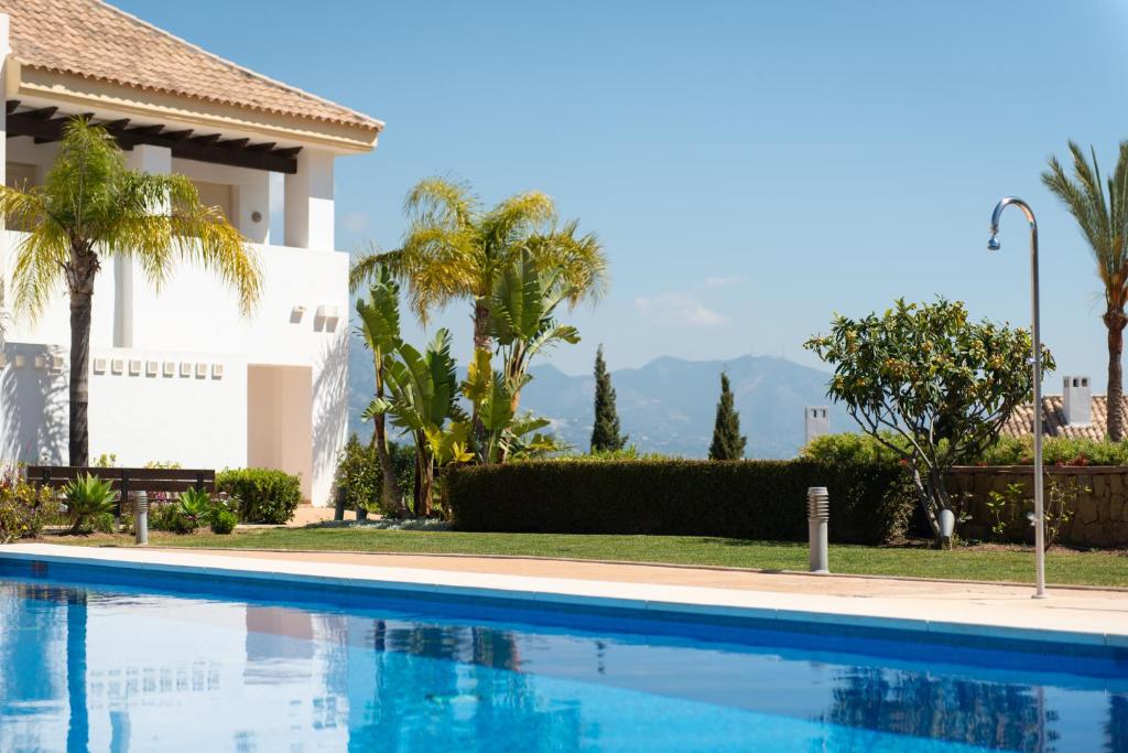 卡拉德米哈斯Luxury townhouse La Cala Golf Resort (Golf, Beach, Nature and Amazing views)的棕榈树屋前的游泳池