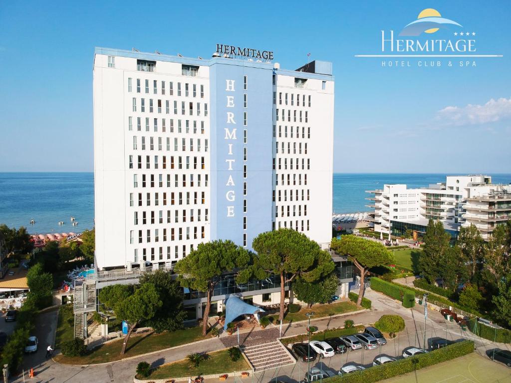 锡尔维玛丽娜Hermitage Hotel的一座大白色的建筑,位于海洋前
