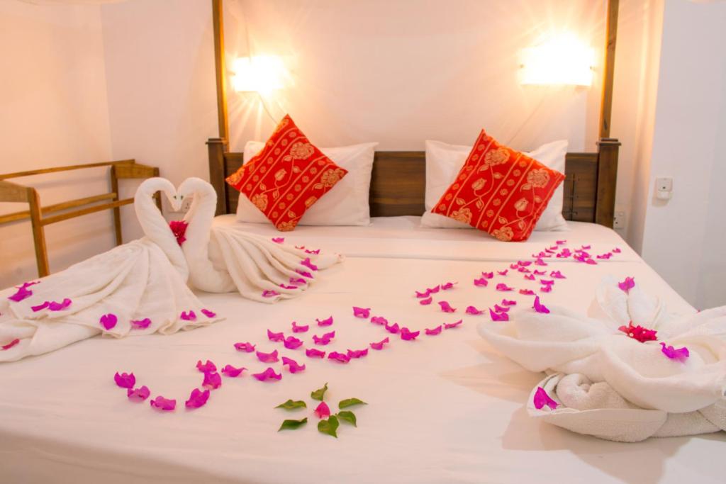阿鲁甘湾East Beach Surf Resort的一张床上有两只天鹅,由花朵制成