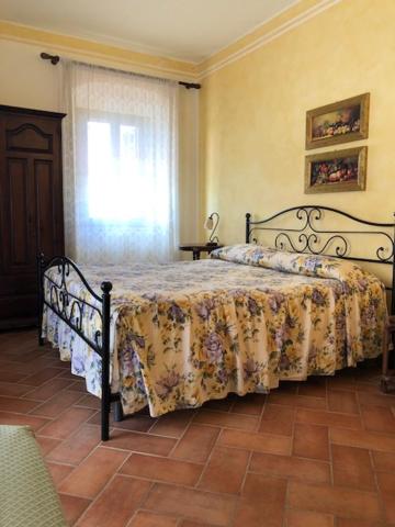 卡帕尔比奥法托丽亚利瓜帝欧雷别墅酒店的一间卧室配有一张带花卉床罩的床和窗户。